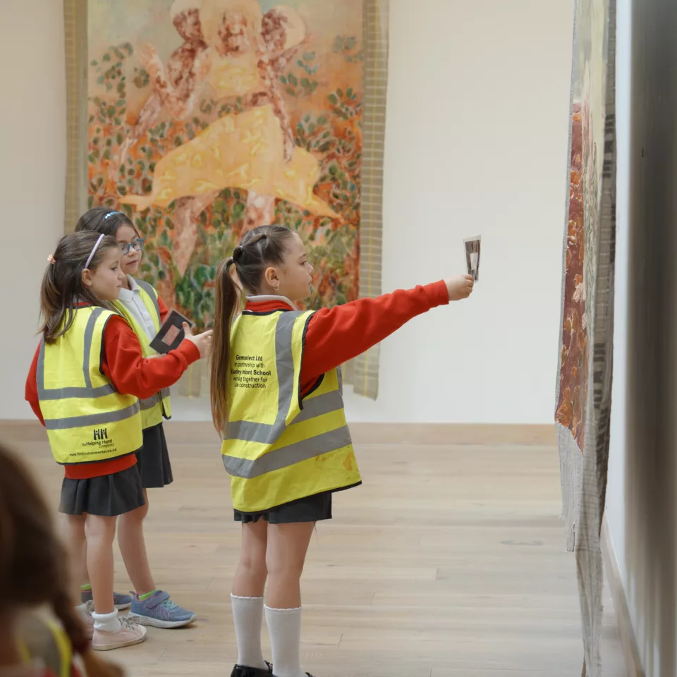 A small group of school students in the upper gallery, looking at the work of Nengi Omuku