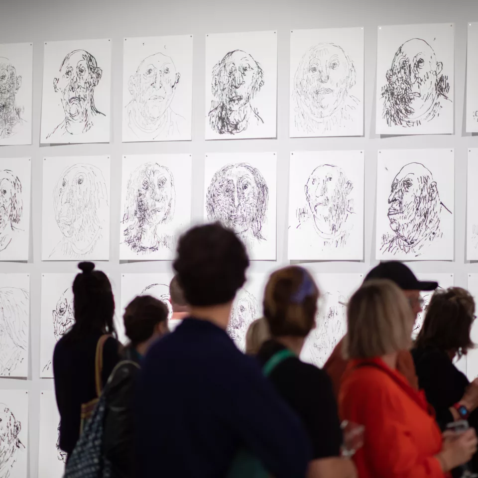 People in a gallery looking at drawings by Quentin Blake