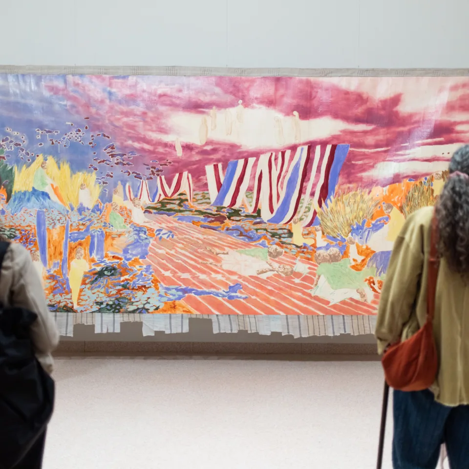 A colour photograph of visitors looking at Nengi Omuku's large scale painting, Eden, at Hastings Contemporary.