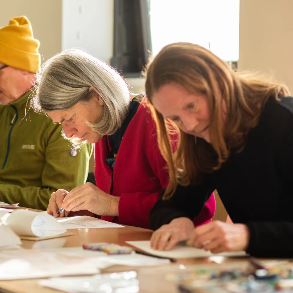 A colour photograph of three adults drawing in our studio
